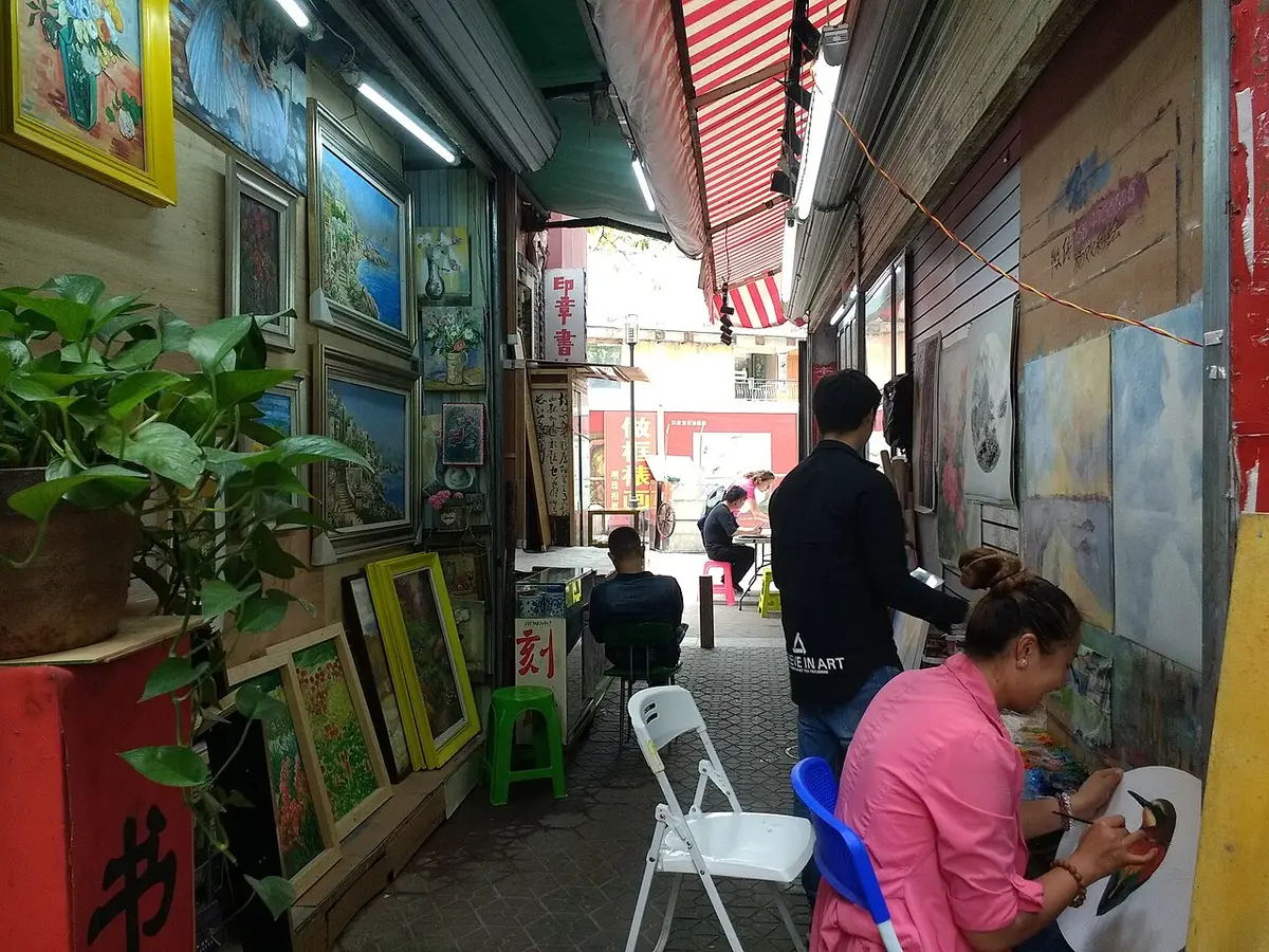 Artists painting at easels in a workshop in Dafen Oil Painting Village, Shenzhen, 2018